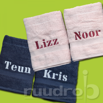 Vier handdoeken. Twee roze en twee blauwe. De namen Lizz, Noor, Teun en Kris erop geborduurd