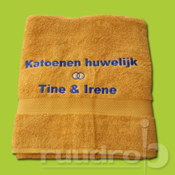 Een oker gele handdoek met geborduurde tekst Katoenen huwelijk Tine en Irene