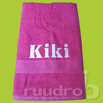 Een roze paarse handdoek met de naam Kiki in het wit erop geborduurd