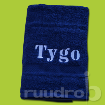 Een donker blauwe handdoek geborduurd met de naam Tygo