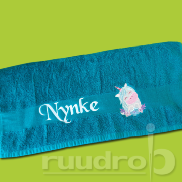 Een turqoise handdoek geborduurd met een unicorn en de naam Nynke