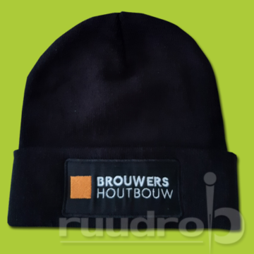 Een zwarte gebreide muts met op de patch het geborduurde logo van Brouwers Houtbouw